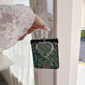 Woven emerald green paisley textured phone case for Samsung Galaxy Z Flip with hanging silver heart compact mirror held in hand.